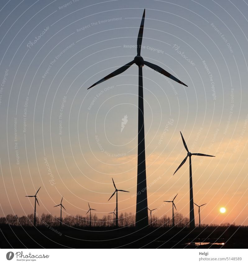 Wind turbines in evening light in front of setting sun Wind energy plant Pinwheel wind farm Power Generation Energy renewable Environmental protection