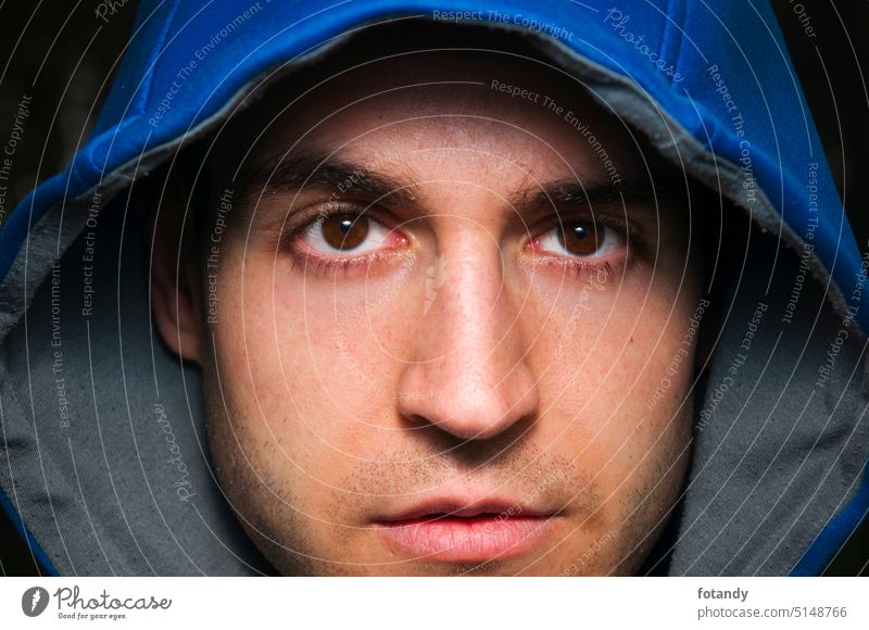 Face of man with blue hood Mann jung Kapuzze Gesichtsporträt Blick in die Kamera Close Up Detail Gesichtsausdruck Kapuze Kopfbedeckung Nahaufnahme Outfit