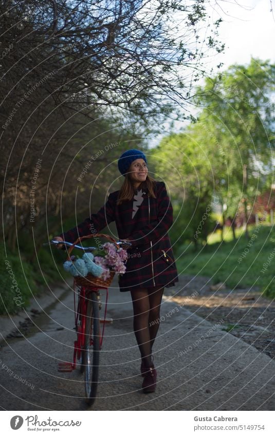 Smiling girl walks along a path with trees with her red bike and flowers. Park Green Nature enjoying Lifestyle Woman youthful Outdoors Happy Happiness Girl Joy