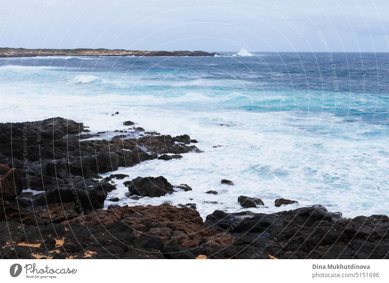 Ocean view landscape with strong waves and rocky landscape. Blue color palette. Surfing spot with big waves. Weather conditions and climate change. Vacation at the beach horizontal backdrop.