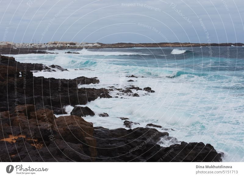 Ocean view landscape with strong waves and rocky landscape. Blue color palette. Surfing spot with big waves. Weather conditions and climate change. Vacation at the beach horizontal backdrop.