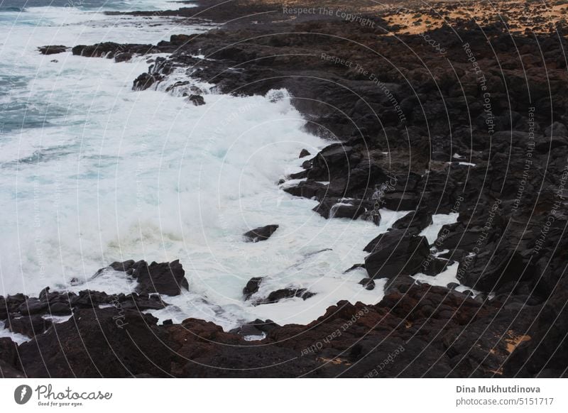 Ocean view landscape with strong waves breaking over rocky landscape. Blue color palette. Surfing spot with big waves. Weather conditions and climate change. Vacation at the beach horizontal backdrop.