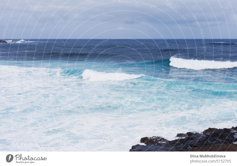 Ocean view landscape with strong waves. Blue color palette. Surfing spot with big waves. Weather conditions and climate change. Vacation at the beach horizontal backdrop.