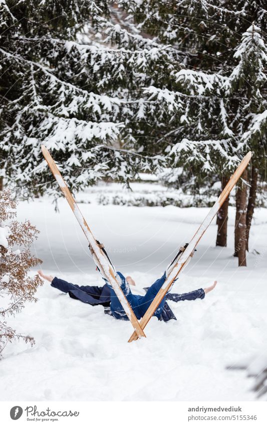 Beautiful cold forest view and skier wearing in skis that lying and relaxing after skiing. Winter day on a slope, pist, skier on the track in winter, process of cross-country skiing in the woods