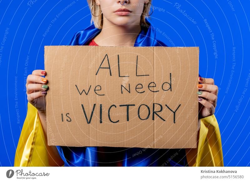 Ukrainian woman with cardboard All we need is victory on blue background. Ukraine protest ukrainian demonstration flag politics freedom political stop symbol