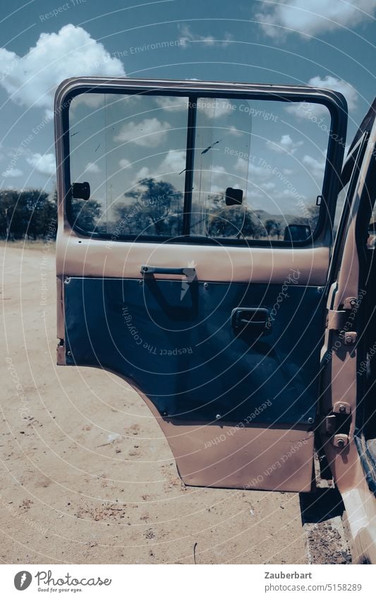 Opened door of off road vehicle on sandy ground in Serengeti in sunshine Offroad vehicle Sand Safari car Driving Robust Territory cross-country allrad Desert