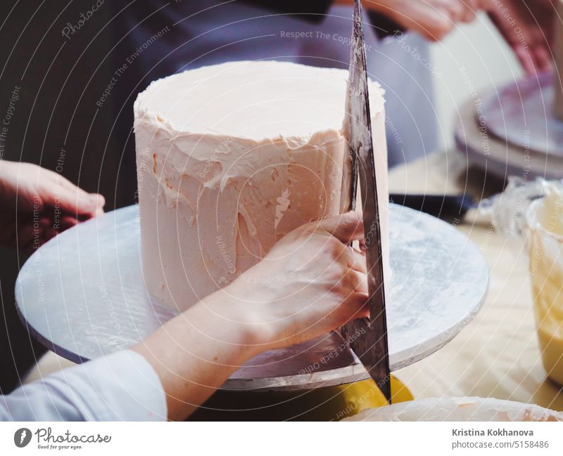 Close Up Of Woman In Bakery Decorating Cake With Icing. Woman's hand levels cream on mousse, decoration cake icing food bakery woman delicious dessert table