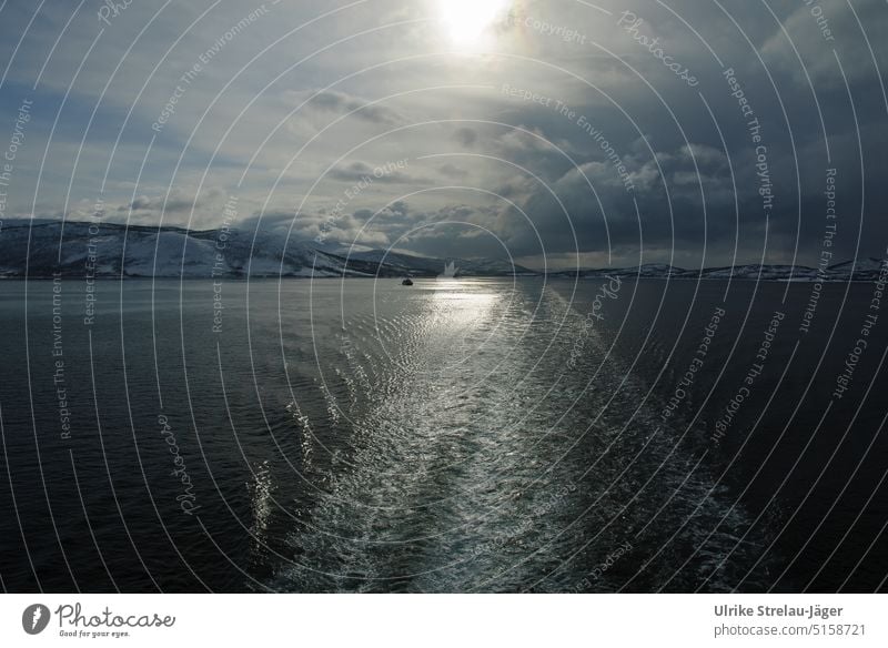 Stern water backlit on winter coast of Norway and a small boat wake Back-light winter sun Sun Winter mood boat trip Cold chill winter cold winterly peace