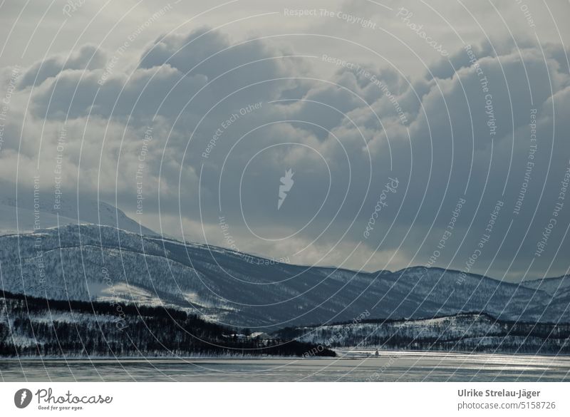 Harbour entrance with small lighthouse, settlement and cloud mountains on winter Norwegian coast Winter winter coast cold sea Waves on the sea Gray clouds