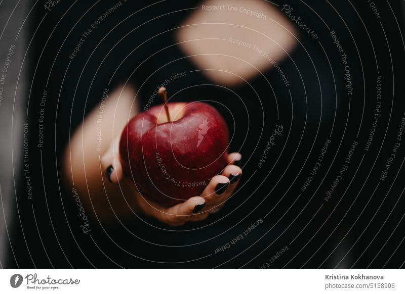 Woman as witch in black offers red apple as symbol of temptation, poison. anger art autumn background beautiful beauty bizarre celebration child contact costume