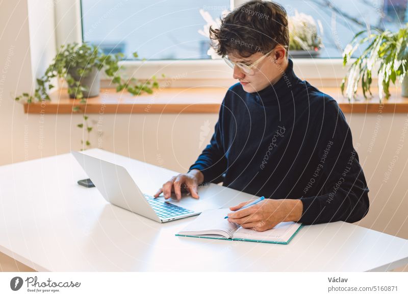 Entrepreneur in his study by the window is thinking of a new concept and strategy that will lead his company to success. A young, goal-oriented guy with glasses and brown hair