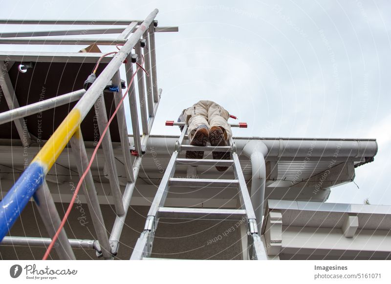 Roofer, worker on the roof, standing on a ladder. Roof work. Scaffolding on the construction site Working man Ladder roofing Architecture Building