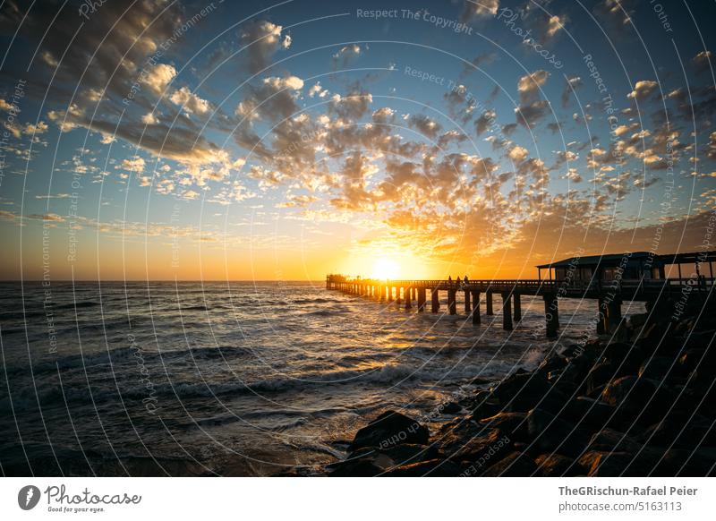 Sunset with jetty and sea Ocean Sky Footbridge stones salt water Sunlight Clouds Moody Horizon Swakopmund Beach Water Evening coast Landscape Nature Twilight