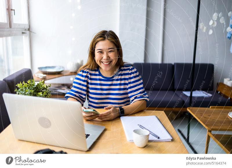 Young woman sitting at desk working on laptop real people millennials student indoors loft window natural girl adult one attractive successful confident person