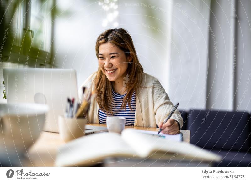 Young woman sitting at desk working on laptop real people millennials student indoors loft window natural girl adult one attractive successful confident person