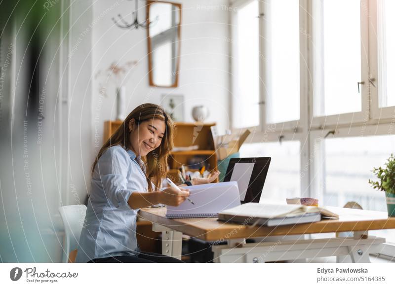 Young woman sitting at desk working on laptop real people millennials student indoors loft window natural girl adult one attractive successful confident person