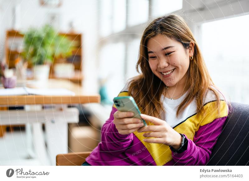 Young woman using smartphone in loft office real people millennials student indoors window natural girl adult attractive successful confident person beautiful