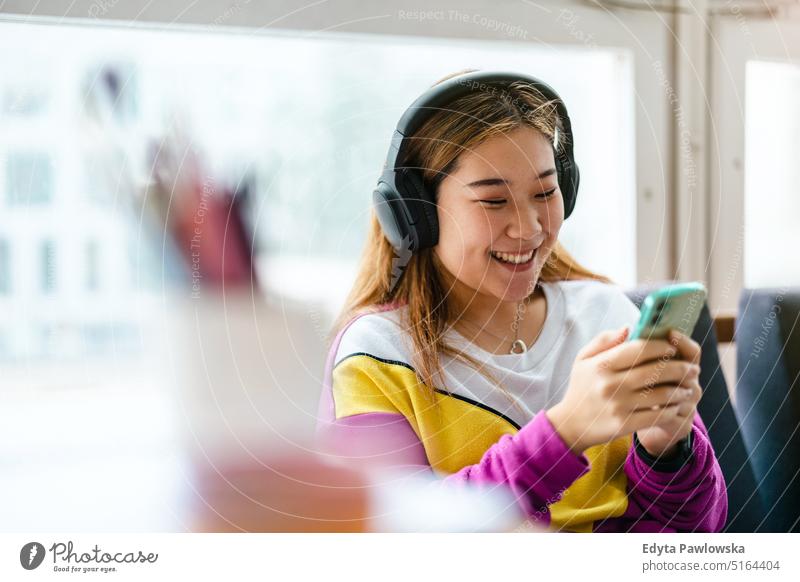 Young woman using headphones while relaxing on the sofa real people millennials student indoors loft window natural girl adult attractive successful confident