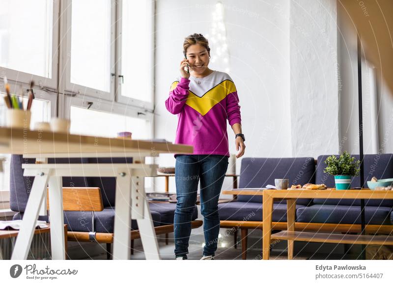 Young woman using smartphone in loft office real people millennials student indoors window natural girl adult attractive successful confident person beautiful