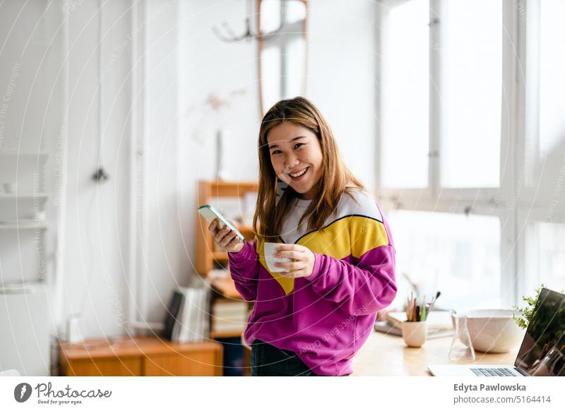 Young woman using smartphone in loft office real people millennials student indoors window natural girl adult attractive successful confident person beautiful