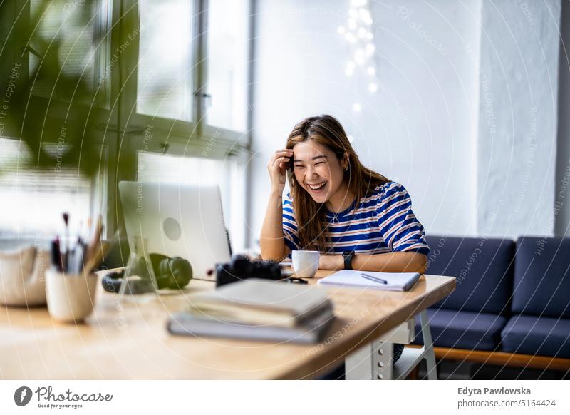 Young woman sitting at desk working on laptop real people millennials student indoors loft window natural girl adult one attractive successful confident person