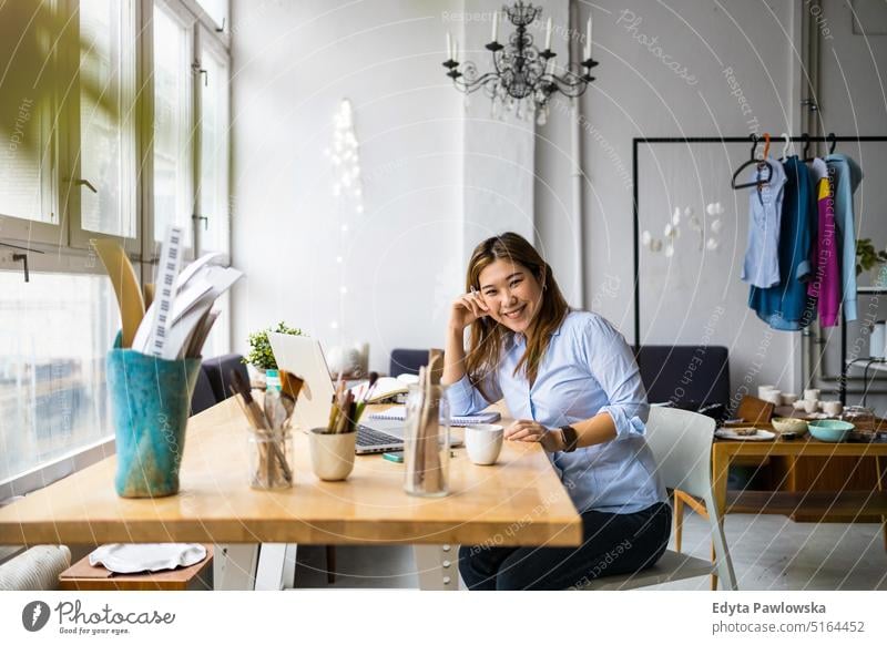 Young woman sitting at desk working on laptop real people millennials student indoors loft window natural girl adult one attractive successful confident person