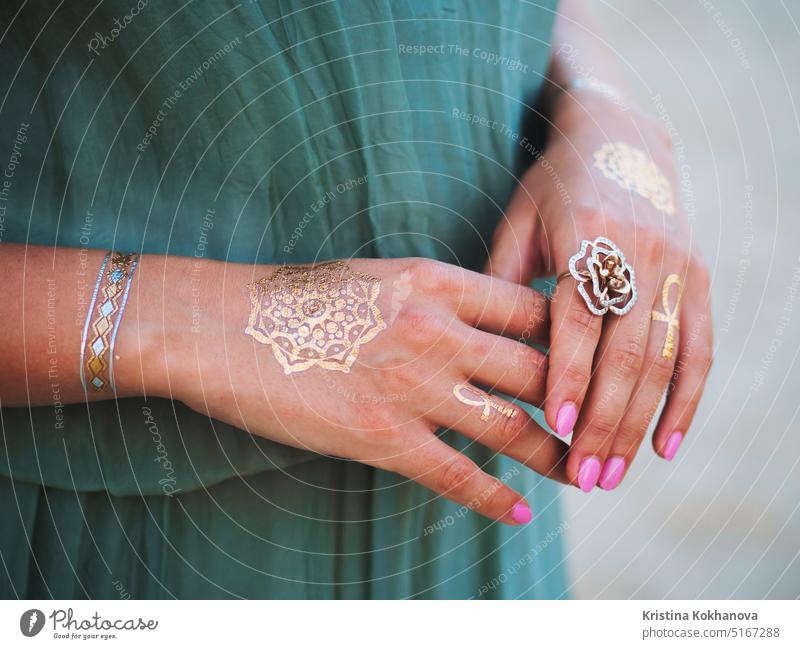 Gold flash tattoos on hands. Close up woman with boho gypsy accessories. fashion young beauty female girl beautiful model person white body bracelet lady