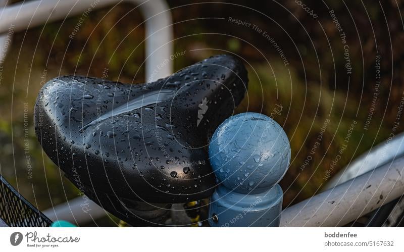 a black bicycle saddle was surprised by the rain, it leans against the upper knob of a blue-gray bicycle stand Bicycle Bicycle rack Exterior shot Wheel