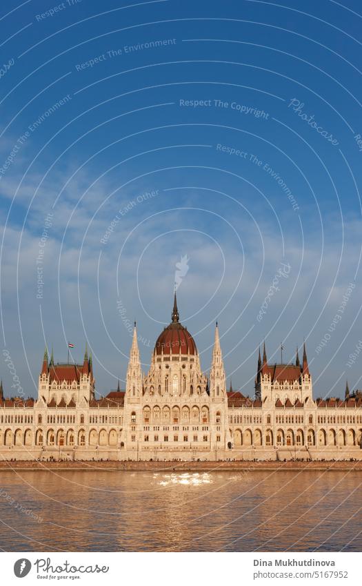 Hungarian Parliament Building in Budapest reflected in the water of Danube, photographed on sunny day with blue sky. Domed Neo-Gothic style architecture. Famous landmark for sightseeing in Hungary postcard view.