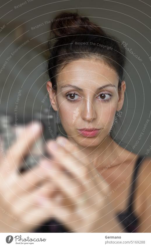 Woman looking at herself In the mirror adult background beautiful beauty brunette bun care caucasian collected concept defocused face female girl hair hand