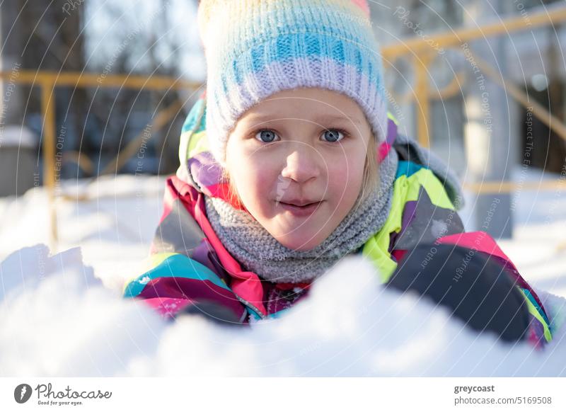 Adorable girl playing on snow winter kid playground child smile portrait positive outerwear warm clothes yard knitted colorful happy season cheerful cold scarf