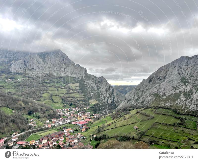 A village down in the valley Nature Landscape Village mountain Mountain Clouds Day daylight Sky Grass trees Green Gray Bird's-eye view Rock fields Environment