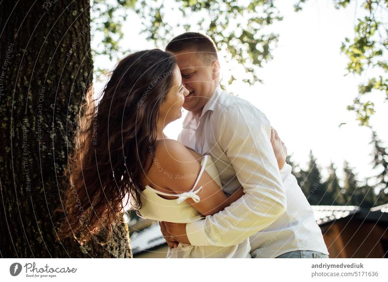 loving young couple having fun outdoors on summer sunny day. Man and woman are hugging near tree in park. valentines day field grass enjoying meadow happy love