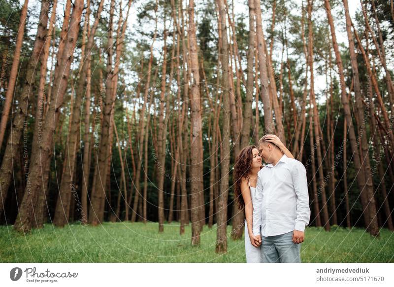 A couple in love beautiful young man and woman are hugging in a summer park on a sunny day. Date outside, well dressed, so excited and lovely happy together