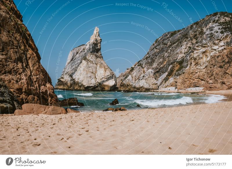 Towering sharp rocky cliff at Praia Da Ursa Beach, Sintra, Portugal. Atlantic ocean waves rolling towards the coast ursa portugal travel vacation sunset rocks