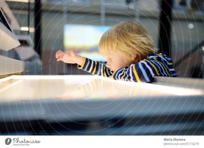 Little caucasian boy is looking an exposition in a scientific museum. Keen child is exploring of exhibits. Education and entertainment for children. Activities for family with kids.