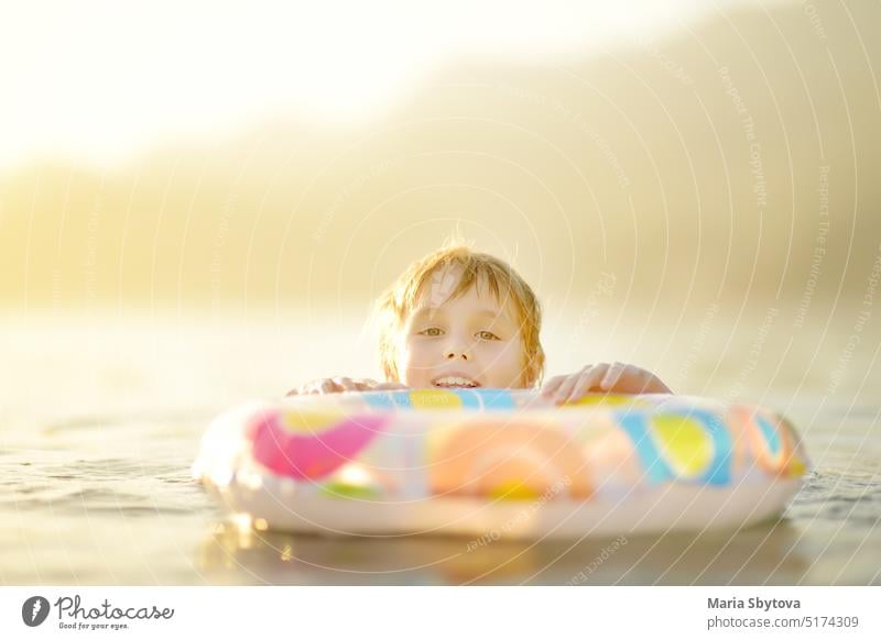 Little boy swimming with colorful floating ring in sea on sunny summer day. Cute child playing in clean water. Family and kids resort holiday during summer vacations.