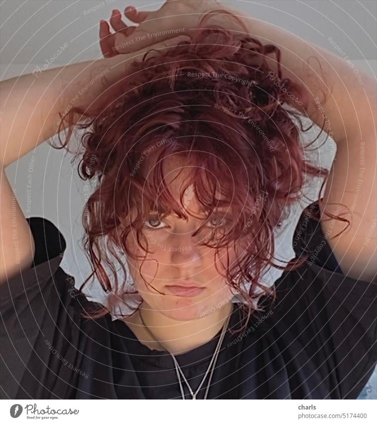 Portrait of a young woman with red curls, staring at the camera. Teenager, schoolgirl, making portraits. Young woman, model, free time, hobbies Interior shot