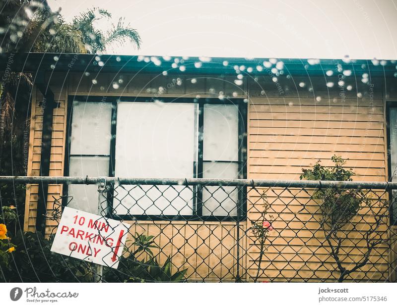 10 MIN PARKING ONLY hangs clearly visible on the fence Facade no parking Signage Signs and labeling Fence Drop Arrow Traffic regulation Front garden vegetation