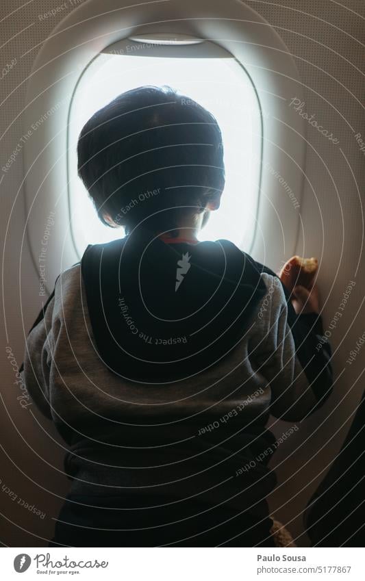 Rear view child looking through airplane window Child childhood Airplane Window Airplane window Sky Vacation & Travel Aviation View from the airplane Clouds