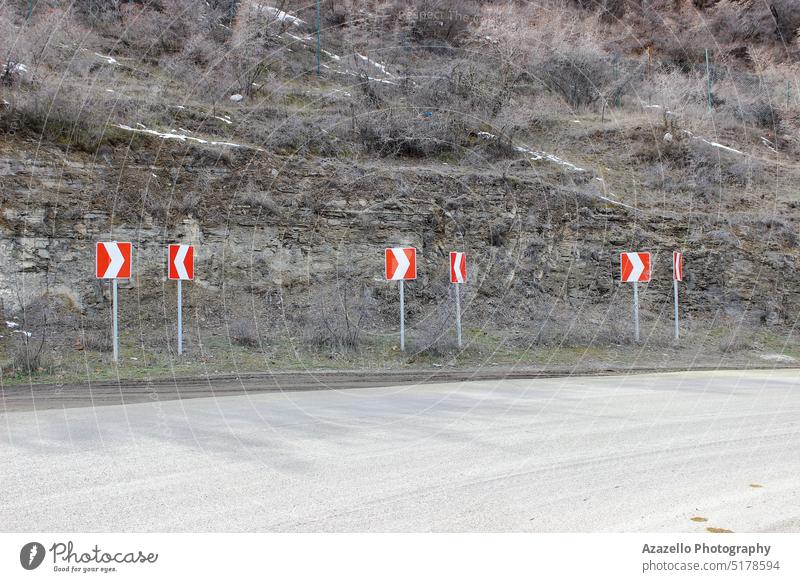 Mountain road with signposts. arrow asphalt background bush cliff cold concept day direction driveway dry earth environment grass group hill icon landscape