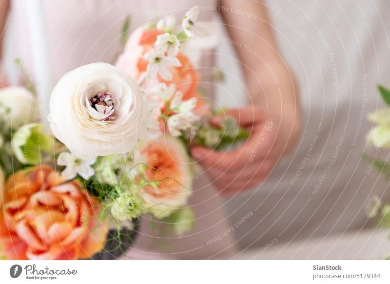 Woman hands touching  a bouquet of flowers. table woman young caucasian hold holding dress white vase candles soft light decoration close up background interior