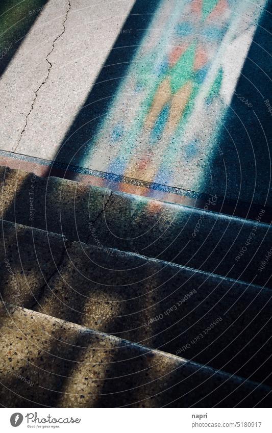 Into the light | Stone steps lead down to an entrance area on the floor of which light from outside throws a colorful pattern of the entrance door stagger