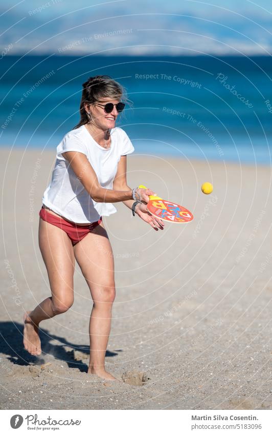 Pregnant woman playing beach tennis on the beach of Alicante in Spain. abdomen adult awaiting baby beautiful beauty belly birth care childbirth family female