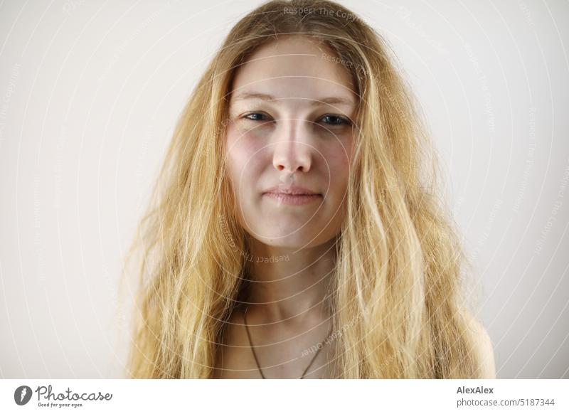 Close portrait of young blonde woman standing in front of white background Fresh Looking into the camera Expectation inside Self-confident feminine Charming