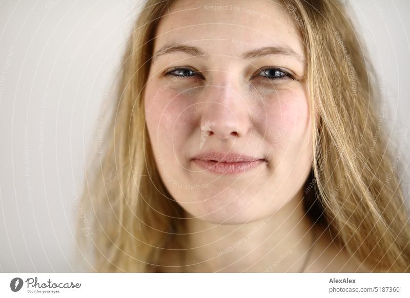 Very close portrait of young blonde woman smiling in front of white background Fresh Looking into the camera Expectation inside Self-confident feminine Charming