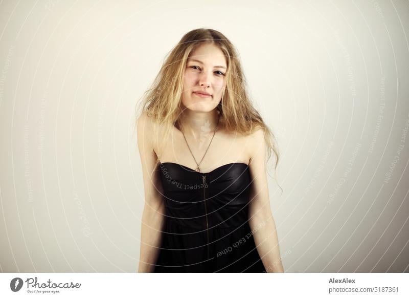 Close portrait of young blonde woman standing in front of white background Fresh Looking into the camera Expectation inside Self-confident feminine Charming