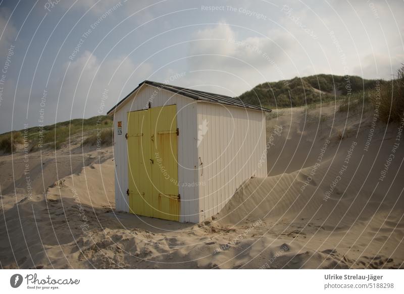 Beach hut with yellow door on dunes surrounded by sand beach hut Wooden hut white beach hut yellow wooden door Wooden door Sandy beach blows around Blown away