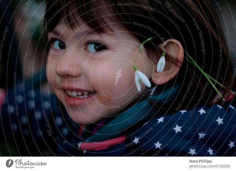 Girl with snowdrop behind ear beautiful girl Toddler brown hair brown eyes Snowdrop Spring Laughter Impish Child portrait pretty Cute Infancy Joy naturally Face