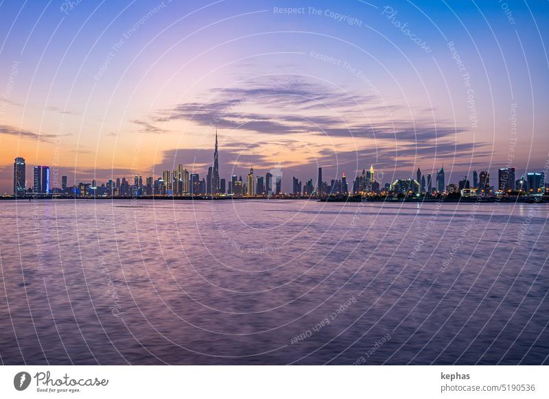 Dubai skyline with skyscrapers and creek at sunset, seen from Dubai Creek Harbour Burj Khalifa Downtown Dubai Skyline Water River Lake sea clouds evening